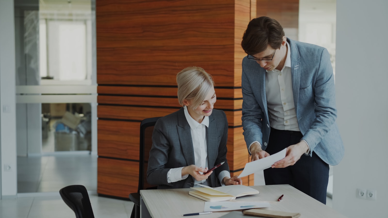 Two colleagues in business attire reviewing a document together at a desk